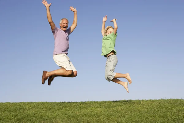 高级男人与孙子在空气中跳跃 — 图库照片