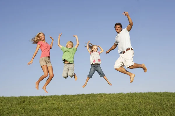 Ungt par med barn hoppa i ett fält — Stockfoto