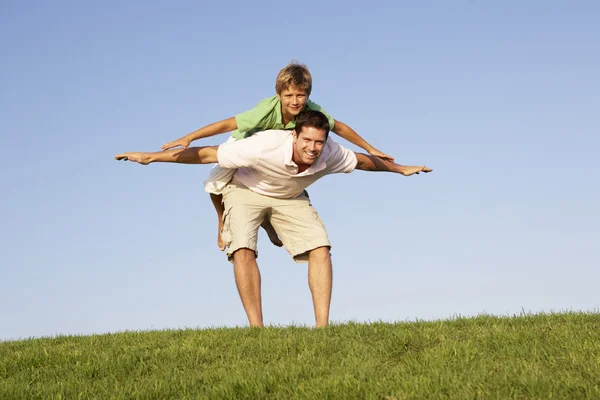 Молодой человек с мальчиком играет в поле — стоковое фото