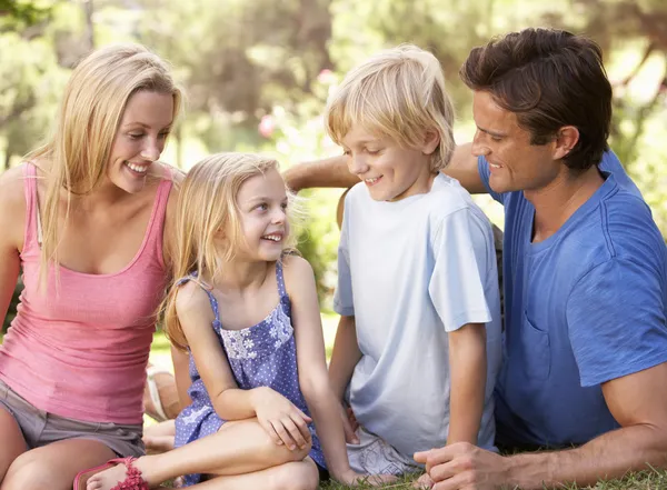 Jonge ouders met kinderen praten in een park — Stockfoto