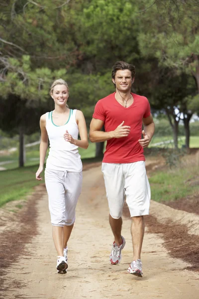 Jovem casal correndo através do parque — Fotografia de Stock