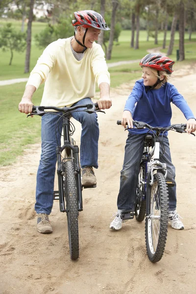 Nagyapa és unokája lovaglás kerékpár-parkban — Stock Fotó