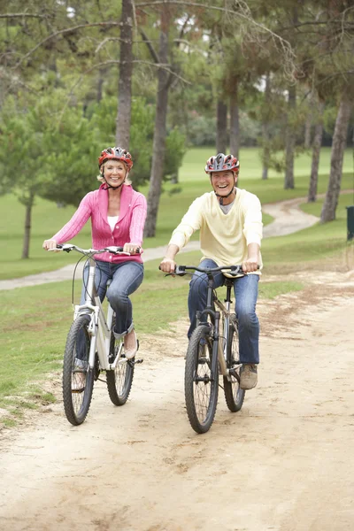 Vedoucí dvojice jedoucí na kole v parku — Stock fotografie