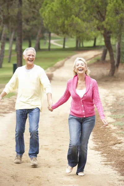 Äldre par njuter av promenad i park — Stockfoto