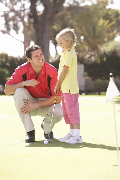 Father Teaching Daughter To Play Golf On Putting On Green Stock Picture