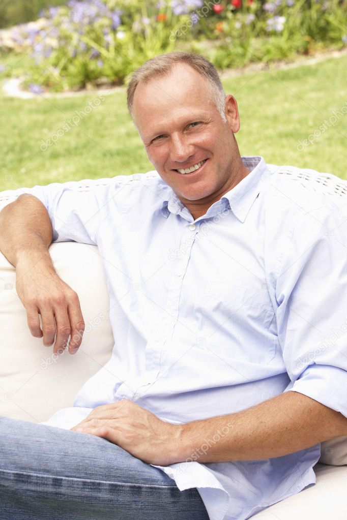 Middle Aged Man Relaxing In Garden Stock Photo by