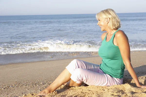 Ανώτερος γυναίκα που κάθεται στο χαλαρωτικό παραλία — Φωτογραφία Αρχείου