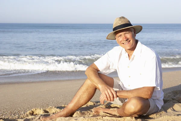 Hombre mayor sentado en la playa relajante — Foto de Stock