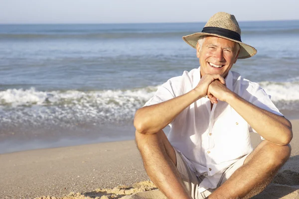 Senior man zit op het strand ontspannen — Stockfoto
