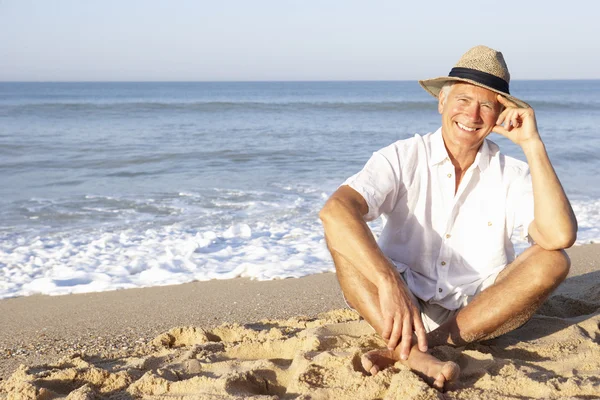 Älterer Mann sitzt entspannt am Strand — Stockfoto