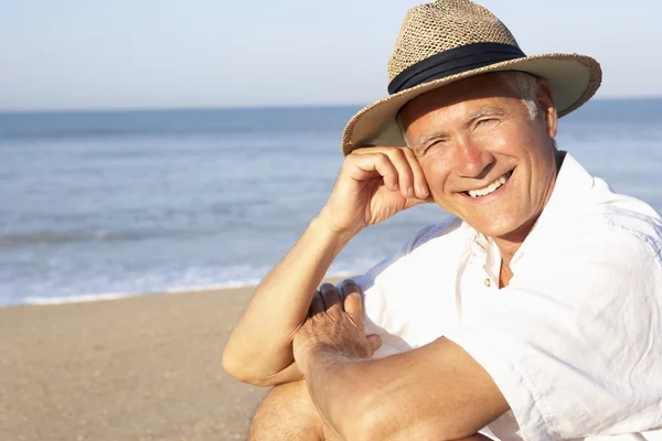 Старший сидит на пляже расслабляясь — стоковое фото