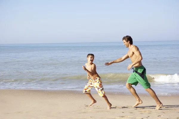 Padre inseguendo giovane ragazzo sulla spiaggia — Foto Stock