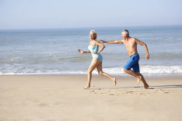 Äldre par kör på stranden — Stockfoto