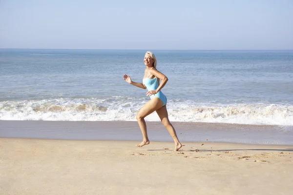 Seniorin läuft am Strand — Stockfoto