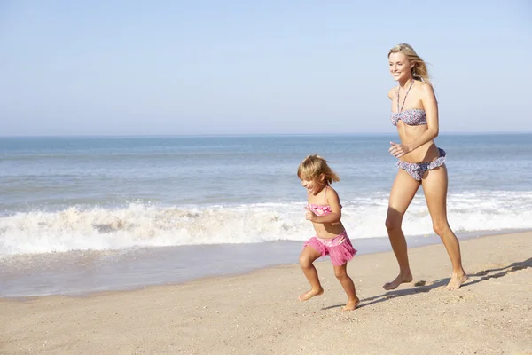 Madre persiguiendo a chica joven en la playa — Foto de Stock