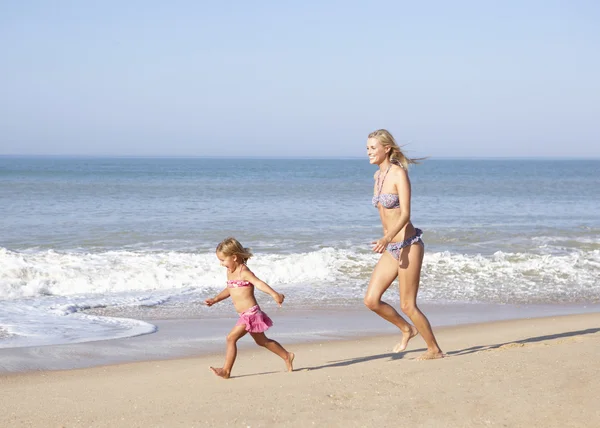 Mãe perseguindo jovem na praia — Fotografia de Stock