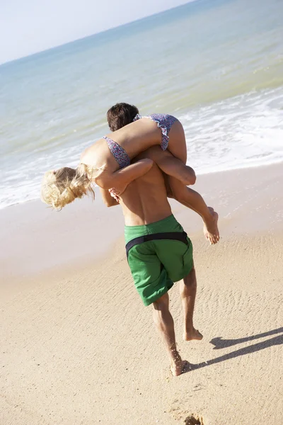Jeune couple jouer sur la plage — Photo