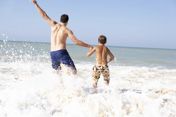 Отец играет с маленьким мальчиком на пляже — стоковое фото