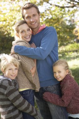 Young family pose in park clipart