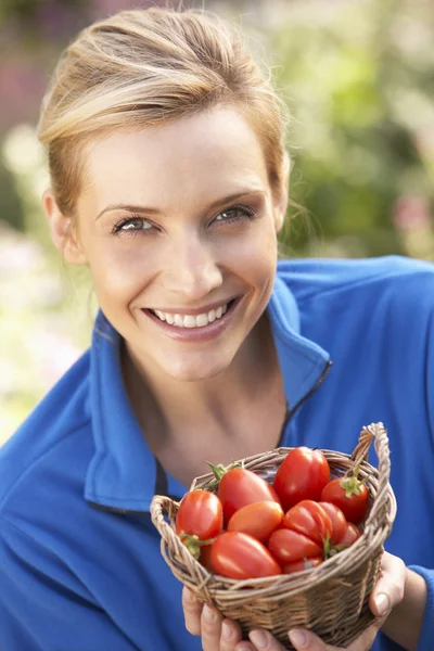 Mladá žena pózuje s rajčaty v zahradě — Stock fotografie