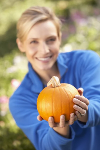 Young woman posing with pumpkin in garden — Stock Photo, Image
