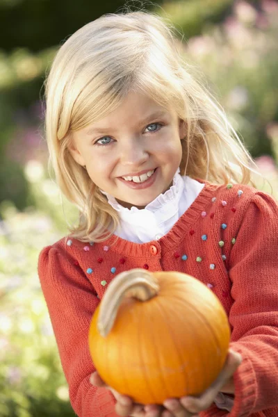 Young girl posing with pumpkin in garden — Stock Photo, Image