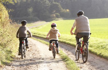 Young father with children ride bikes in park clipart