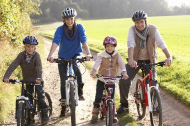 Young family pose with bikes in park clipart