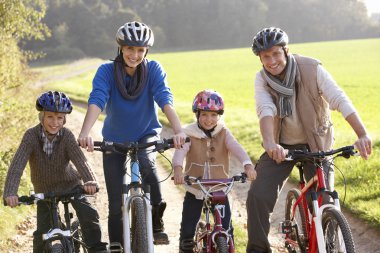 Young family pose with bikes in park clipart