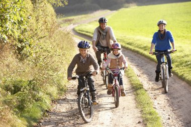 Young parents with children ride bikes in park clipart