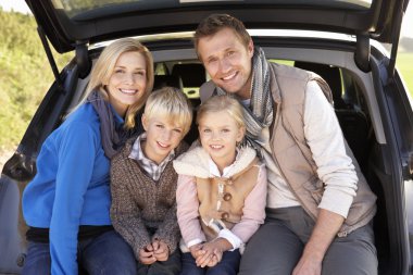 Young family pose together at rear of car clipart