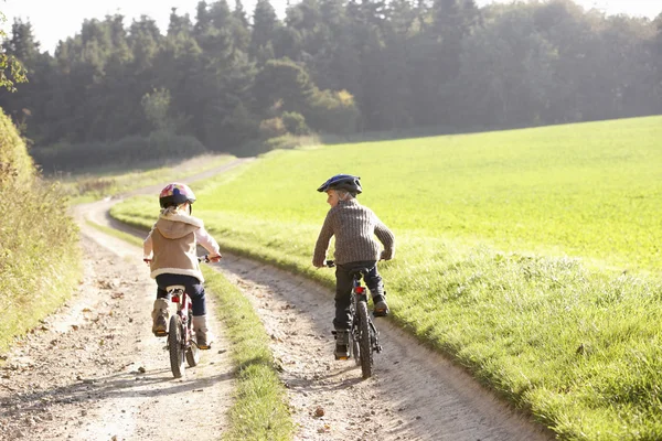 Två barn rida cyklar i parken — Stockfoto