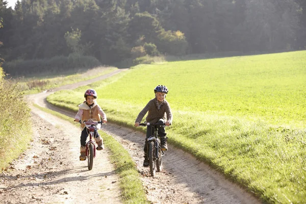 Twee jonge kinderen rijden fietsen in park — Stockfoto