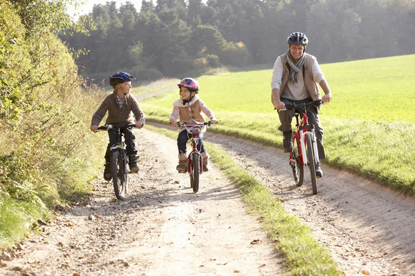 Young father with children ride bikes in park — Stock Photo, Image