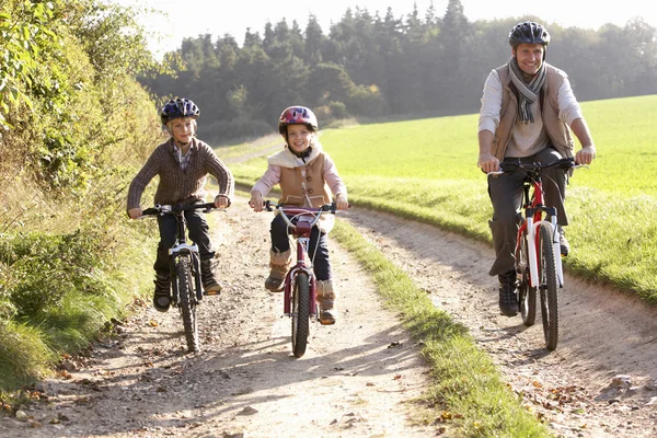 Padre joven con niños montar bicicletas en el parque —  Fotos de Stock