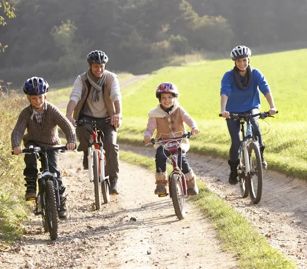 Young parents with children ride bikes in park — Stock Photo, Image
