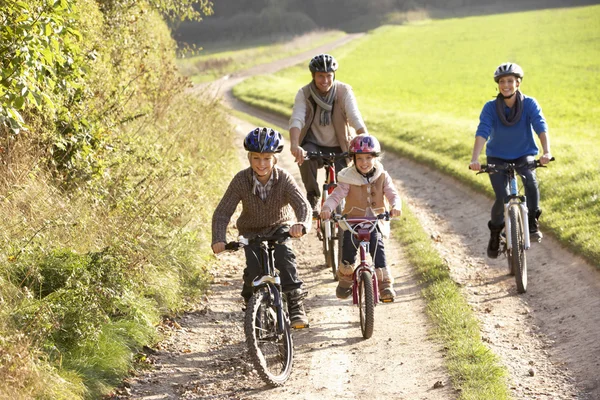 Padres jóvenes con niños montan bicicletas en el parque — Foto de Stock