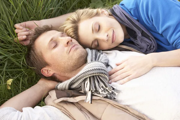 Jovem casal deitado juntos na grama — Fotografia de Stock