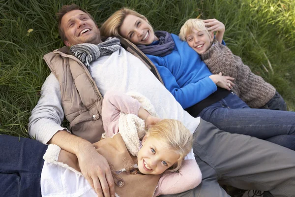 Jovem família deitada juntas na grama — Fotografia de Stock