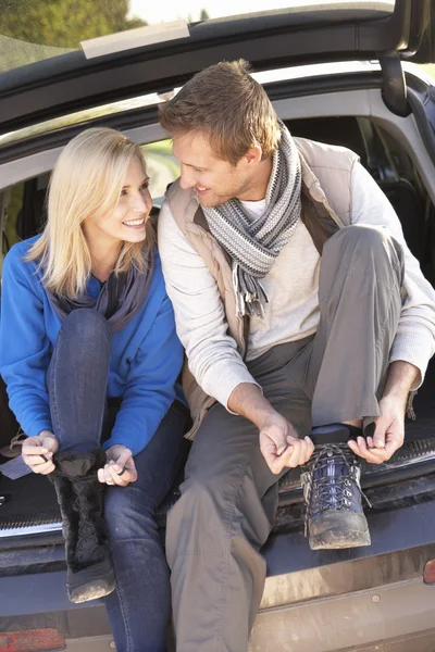 Junges Paar schnürt Stiefel am Heck des Autos — Stockfoto