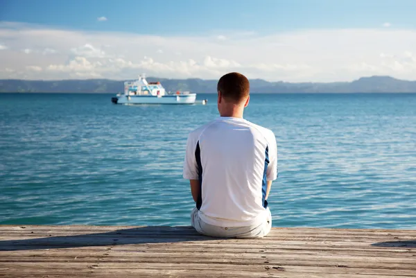 Jeune homme se détendre assis sur le quai — Photo