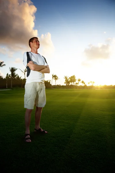Young man on green field and sunset — Stock Photo, Image