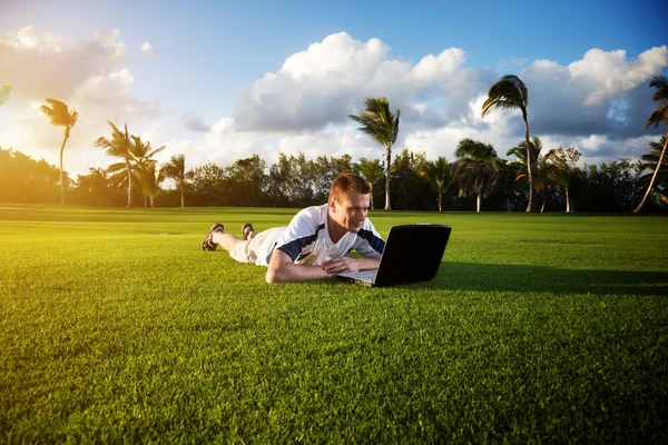 Young man whith notebook on the green field — Stock Photo, Image