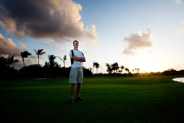 Jongeman op groen veld en zonsondergang — Stockfoto