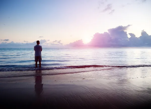Gelukkig jonge man in zee en zonsopgang — Stockfoto