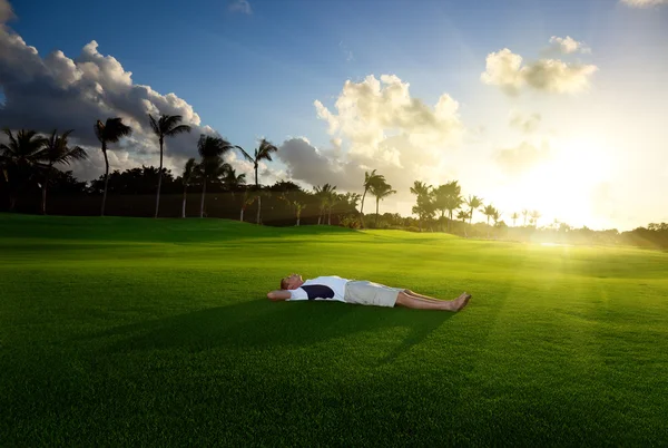 Mladý muž relaxovat na zelené trávě — Stock fotografie
