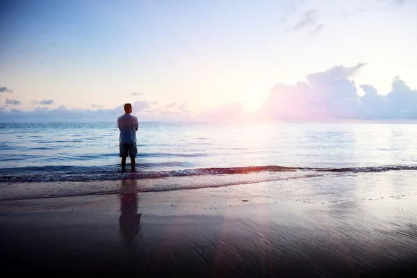 Glücklicher junger Mann im Meer und Sonnenaufgang — Stockfoto