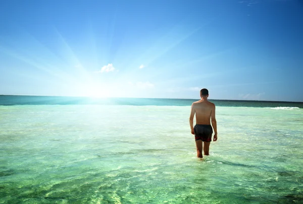 Giovane uomo a piedi nel mare dei Caraibi — Foto Stock