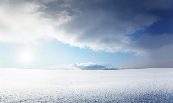 Снежное поле и облачное небо — стоковое фото