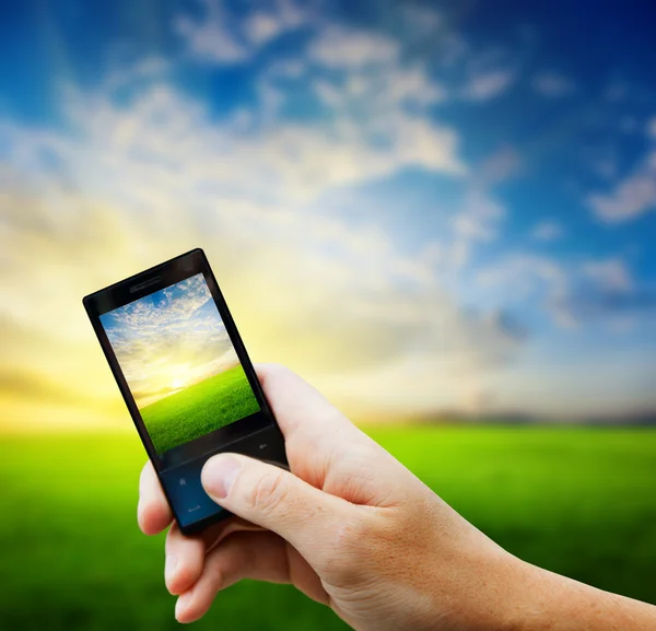 Mobiltelefon i handen och land solnedgång — Stockfoto